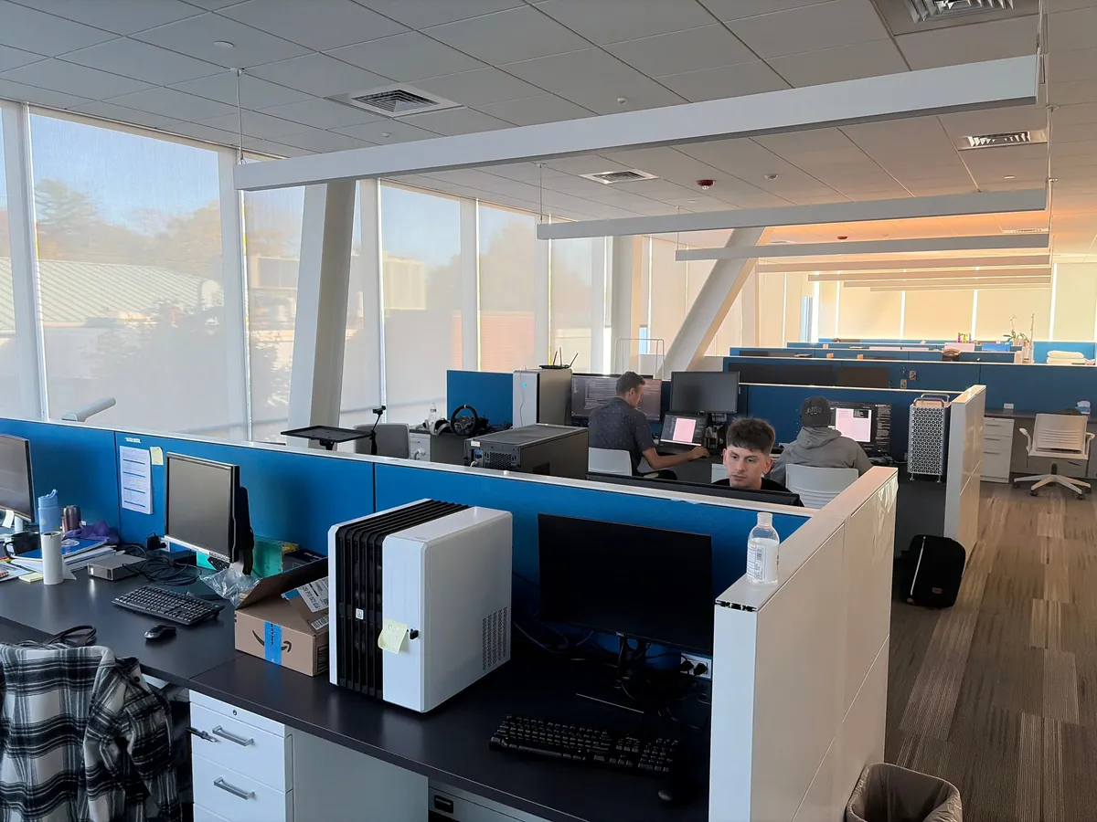 Graduate students working at cubicle workstations in the sunlit FCAE graduate lounge