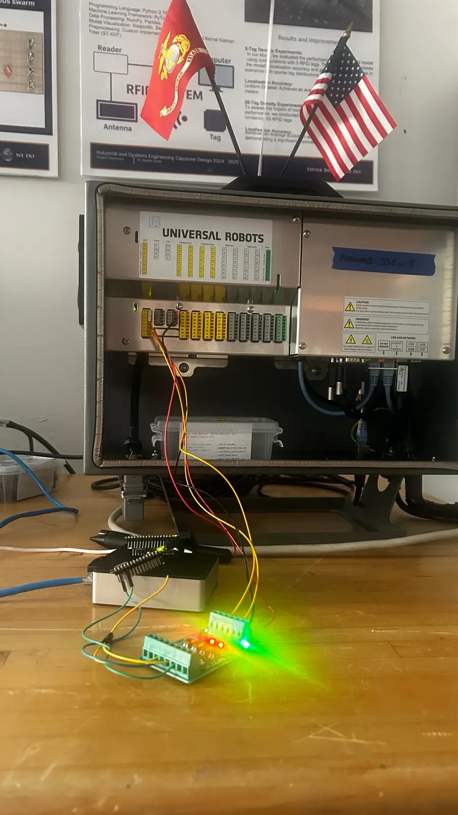 Edge node breadboard with lit status LEDs wired into the safeguard input terminals of a Universal Robots UR5 controller cabinet